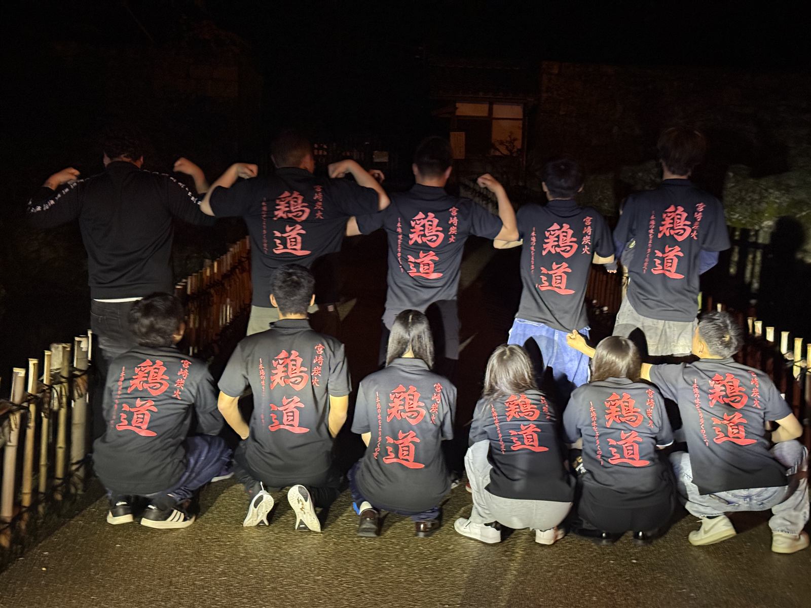 鶏道の筆文字Tシャツを着たスタッフたちの集合写真（後ろ姿）